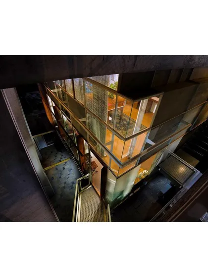 The studio's interior is organized as a series of "levitating" galleries suspended from the main concrete portals. This night view from below highlights the transparency and layered complexity of the structure, which glows like a lantern.