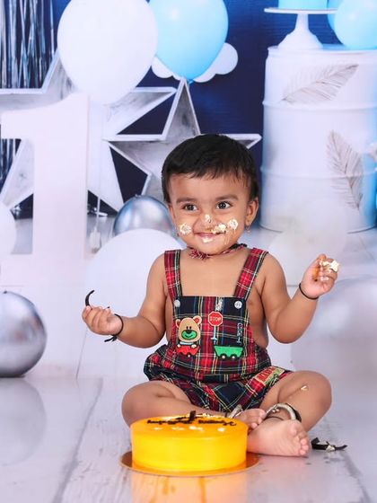 Another angle from the yellow cake cake smash, showing the baby with a little bit of frosting on his face. The "ONE" sign and star decorations complete the birthday theme.
