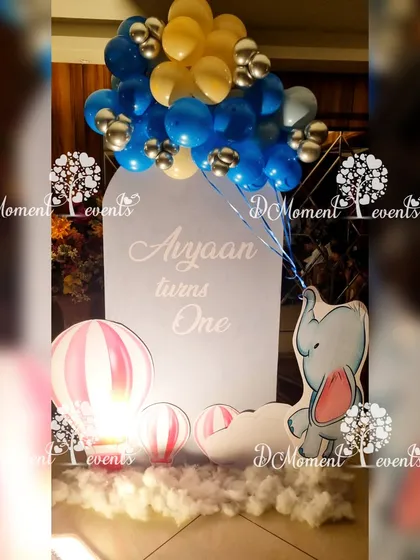 A charming and budget-friendly space-themed photo spot. The setup includes a simple backdrop, an elephant prop holding balloons, and hot air balloon cutouts.