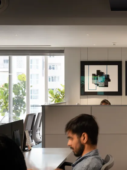 An employee at their desk, illustrating how the space functions in a real-world context. The design provides ample personal workspace while being part of a larger, connected office environment.