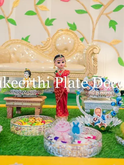 A wider view of the baby shower setup, showing the variety of platters and props used. From baby dolls in cradles to beautifully arranged sweets, every element is thoughtfully placed.