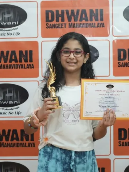 A smiling student proudly holds her certificate and trophy.