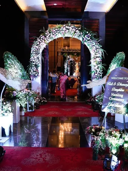 The entrance to the butterfly-themed naming ceremony, featuring a floral arch, white Moroccan-style lanterns, and large, elegant butterfly wings.