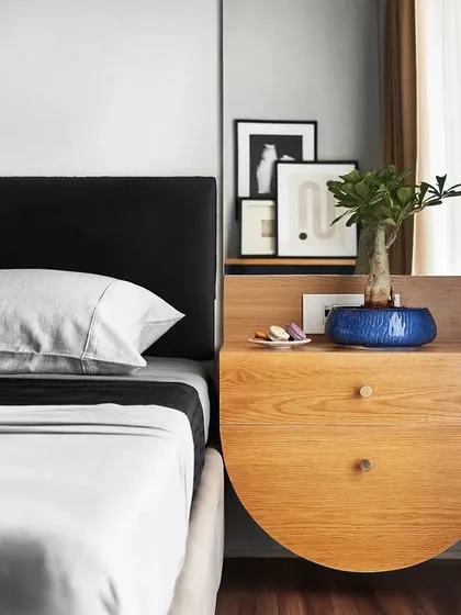 In 'The Pier' bedroom, a custom floating nightstand with a semi-circular design adds a unique touch. The space is defined by a monochrome palette and clean, architectural lines.