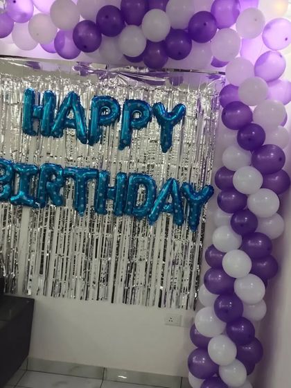 A simple yet bold birthday setup with a purple and white balloon arch and blue 'Happy Birthday' foil letters.