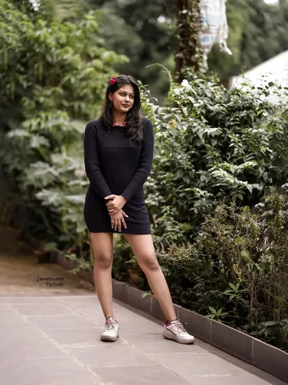 A full-length shot of a simple and chic black sweater dress paired with sneakers, perfect for a casual day out.