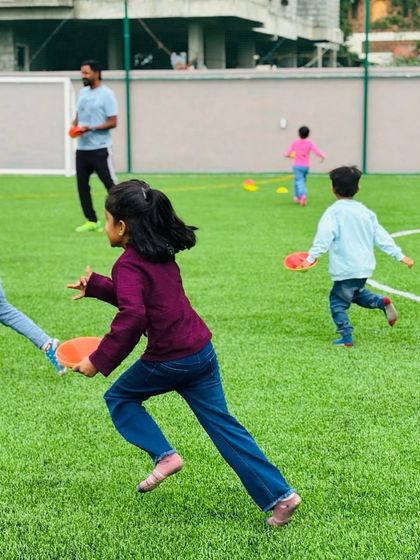 Children run with joy and energy across the turf field during an outdoor game. I ensure that my camps include plenty of time for free play and structured sports to keep children active and engaged.