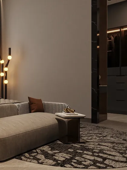 A view of the seating area at the foot of the bed, with a glimpse into the adjoining walk-in closet. The houndstooth pattern on the sofa adds a classic touch.