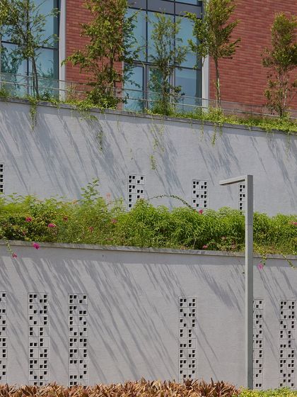 Here, the integration of greenery is not just horizontal but vertical. The terraced planters and perforated 'jali' walls at the Wipro campus help mitigate heat gain on the building facade while creating a visually interesting texture of light, shadow, and nature.