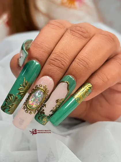 A close-up of the regal green and gold set, focusing on the central accent nail with its large, iridescent gem set in a sculpted gold frame.
