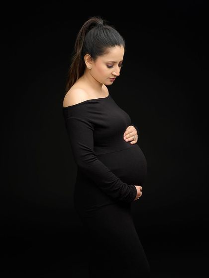 A simple yet powerful profile shot in a form-fitting black dress. The clean, dark background and classic pose create a timeless and sophisticated silhouette portrait.