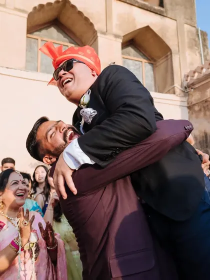 A candid moment of pure joy as the groom is lifted up by a friend during the baraat celebrations.