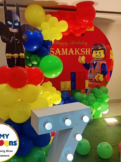 A close-up of a LEGO-themed party, showing a LEGO Batman cutout and a large light-up number '7'.