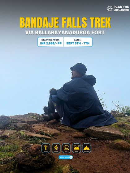 A trekker in a poncho sits peacefully on the misty trail of the Bandaje Falls trek. This offbeat trek offers serene moments and stunning views of the waterfall.