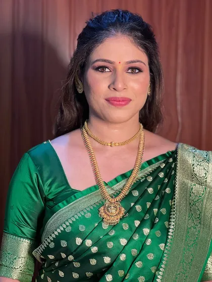 A simple and elegant look for a guest, featuring a beautiful green silk saree and traditional gold jewellery.