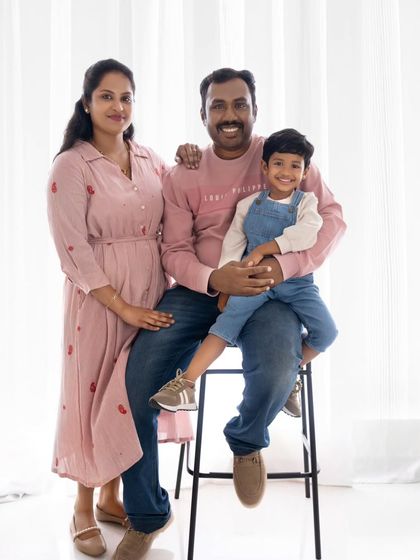A classic, happy family-of-three portrait. Their coordinated outfits and bright smiles make this a perfect keepsake.