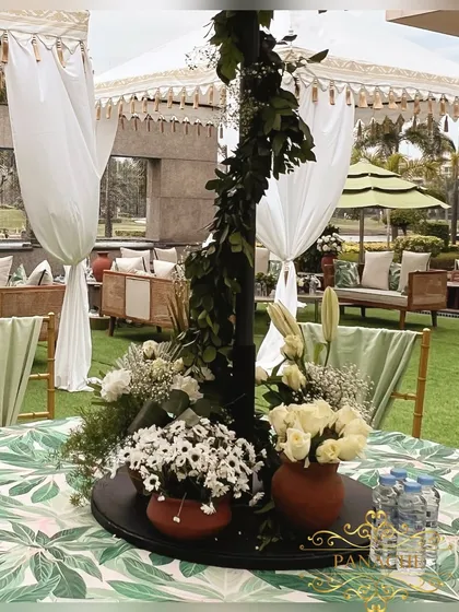 A close-up of a centerpiece, featuring an arrangement of white and green flowers in terracotta pots on a black platter.