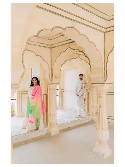 A beautifully composed shot using the repeating arches of a palace corridor to frame the couple, creating a sense of depth and grandeur.