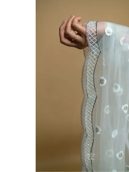 A detail shot of the baby blue ensemble's tulle scalloped dupatta, featuring delicate floral embroidery that adds a touch of ethereal beauty.