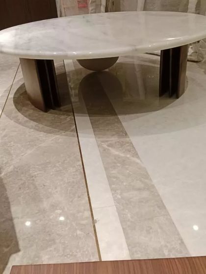 A beautiful oval coffee table with a white marble top and a sturdy wooden base. Its clean, elegant lines make it a perfect centerpiece for a modern and sophisticated living room.