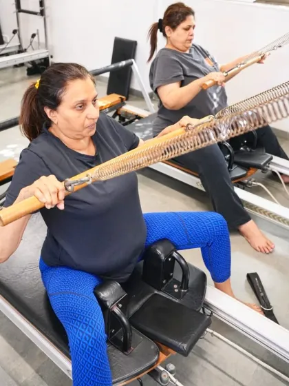 Two clients work together on a unique piece of equipment, focusing on upper body and core strength. The spring resistance provides a constant challenge, toning the muscles without impact.