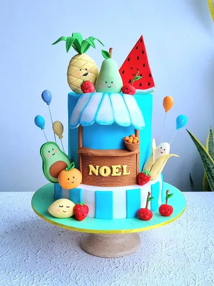 A full view of the fruit-themed cake on its stand.