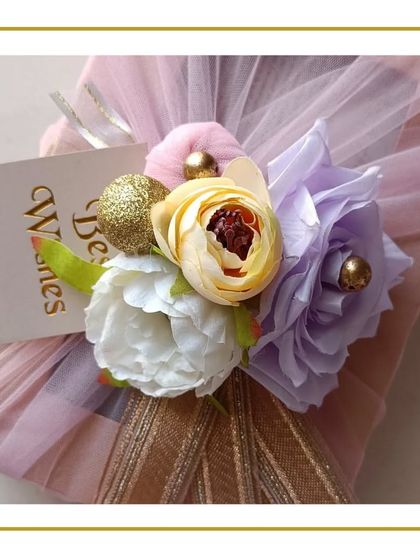 This wedding gift for a dear friend is wrapped in layers of pastel-colored net fabric. I added a bouquet of artificial flowers and a 'Best Wishes' card to create a dreamy and celebratory look.