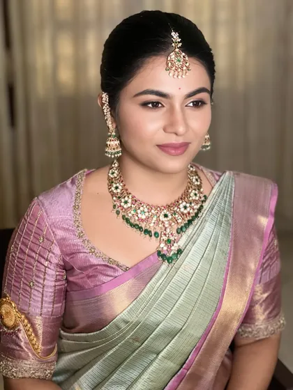 Soft, dreamy, and utterly timeless. This look is perfect for daytime ceremonies, featuring a delicate makeup application that enhances the bride's natural beauty and complements her pastel green and baby pink Kanjeevaram saree.