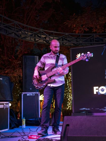 A bassist lays down the groove during a nighttime performance at the World Food Carnival, highlighting how the energy continues even after the sun goes down.