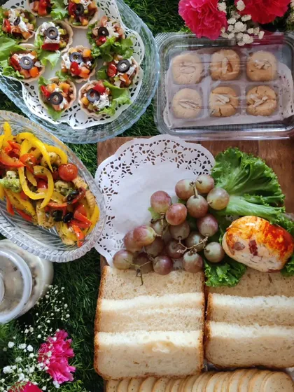 An example of a custom high-tea or breakfast hamper we created. This beautiful spread includes bite-sized tarts, fresh sandwiches, a paprika-dusted cheese ball, homemade cookies, and fresh grapes, showing the variety we can offer for any occasion.