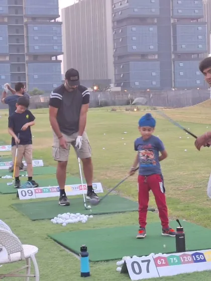A family enjoys a day at the range. A coach guides a young boy, while his father looks on, making it a shared learning experience.