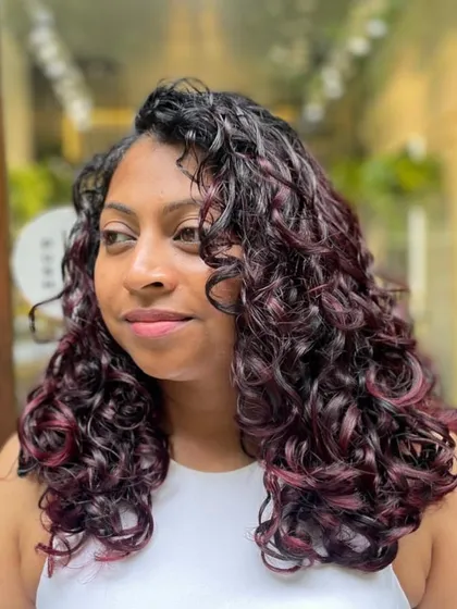 A beautiful 'Cherry Cola' balayage that frames the face perfectly. My technique ensures that the color enhances your features and the shape of your curly cut, giving you a complete, cohesive look.