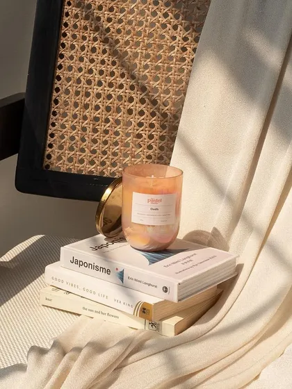 A beautifully styled product shot for The Pastel Studio, featuring their Oudh scented candle in a cozy, sunlit setting.