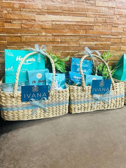 A pair of the Ivana by Jindals corporate hampers, showing the consistent branding and elegant presentation in kauna grass baskets.