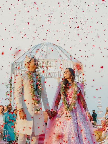 The couple looking up with joy as petals rain down on them, a perfect shot of their happiness.