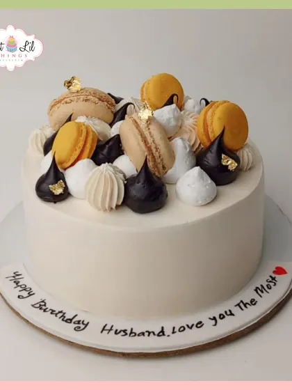 An elegant and delicious-looking cake for a husband's birthday, topped with macarons and meringue kisses.
