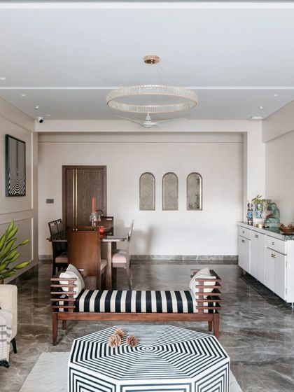 A wide view of this living and dining area shows how different zones can coexist harmoniously. The striped bench, geometric coffee table, and elegant dining set are all tied together by a consistent color palette and a focus on clean lines.