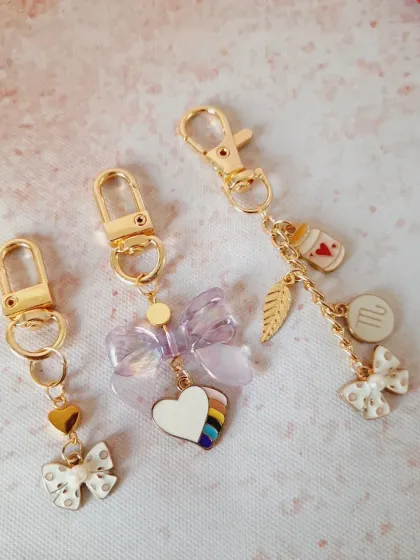 A trio of custom bag charms, each with its own unique personality. From a simple bow and heart to a personalized zodiac charm, these show the endless ways you can style your bag.