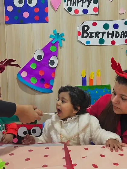 An instructor helps the birthday girl have a bite of her cake.