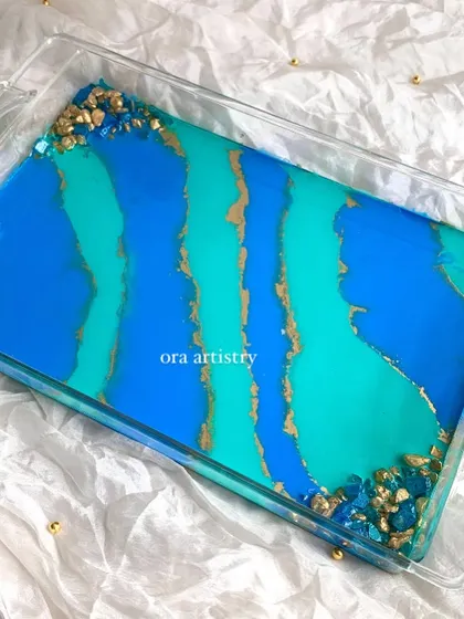 A beautiful and functional serving tray with a blue, teal, and gold abstract design. The geode crystal corners add a touch of luxury.