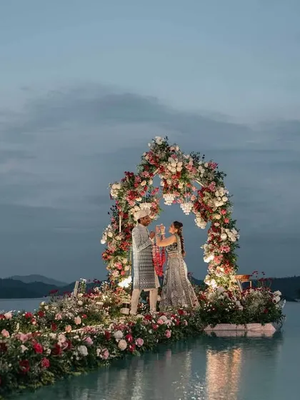 Another shot of the stunning infinity pool Varmala ceremony. The twilight sky and the reflection of the floral arch on the water create a scene of unparalleled beauty.