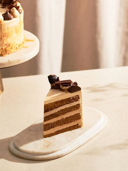 A slice of the Caramel Cake, showing the layers of vanilla sponge and caramel ganache buttercream. It's a perfect example of a smooth, sweet, and satisfying dessert.