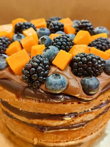 A beautiful blend of flavors in this naked-style cake. A moist, egg-free vanilla sponge is layered with 54% Belgian dark chocolate ganache and topped with fresh mangoes and summer berries.