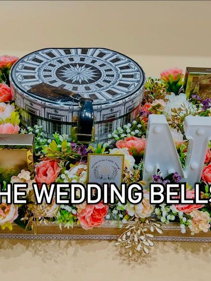 A grand floral hamper for a wedding, featuring a large decorative box, chocolates, and personalized light-up initials.