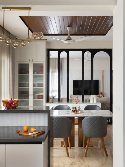 This perspective from the kitchen island shows how the dining and living areas connect. The wooden false ceiling over the dining table helps define the space, while the metal partition adds a layer of visual interest.