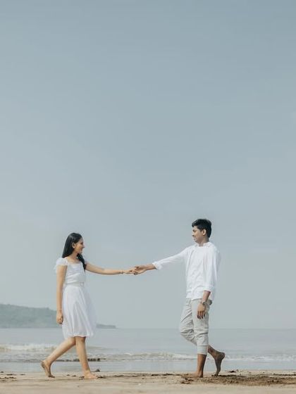 A simple, beautiful moment of a couple walking hand-in-hand on the beach, captured with a clean and airy aesthetic.