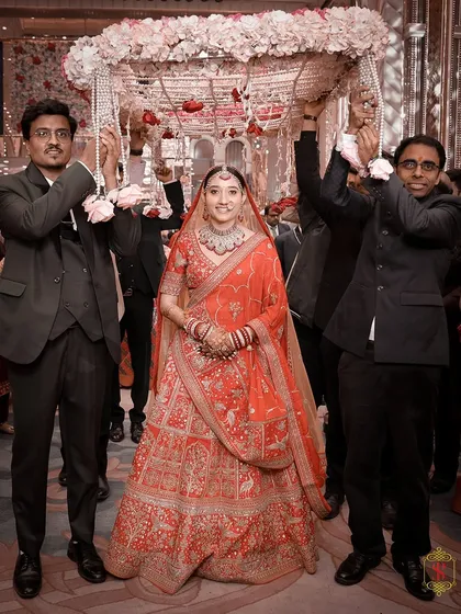 The bride's grand entrance under a traditional phoolon ki chaadar, held by her brothers. This is a classic wedding moment, filled with emotion and anticipation.