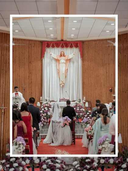 A wide shot of a Christian wedding ceremony, capturing the couple at the altar under the serene gaze of a statue of Jesus.