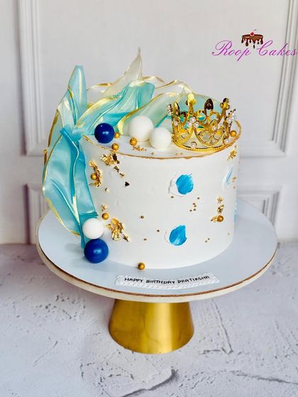 Royalty in every bite. This elegant cake features abstract blue sails, gold leaf, and a small crown, creating a modern and regal design for a special birthday.