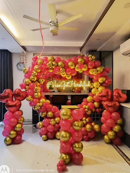 I can create personalized decor for your engagement or anniversary party, like this heart-shaped balloon arch in pink and gold. The custom neon sign featuring the couple's wedding hashtag, "#VaseGotHarshified", makes the setup unique and personal.